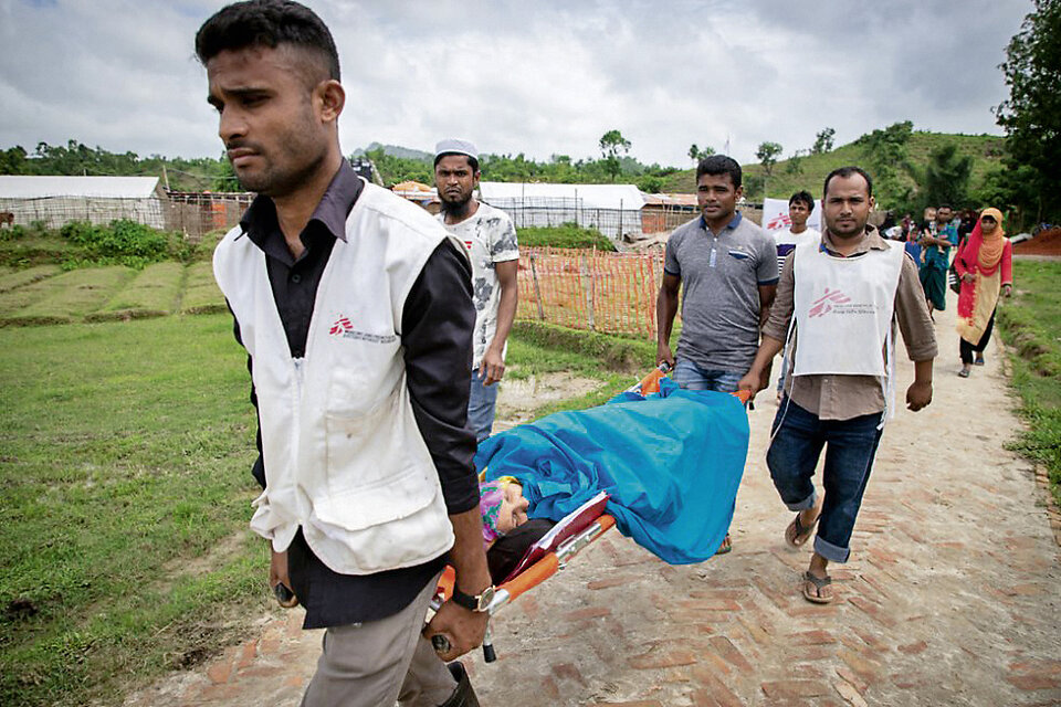 Abb. 2: Krankenpfleger transportieren eine Person in einem Flüchtlingslager für Rohingya auf einer Krankentrage