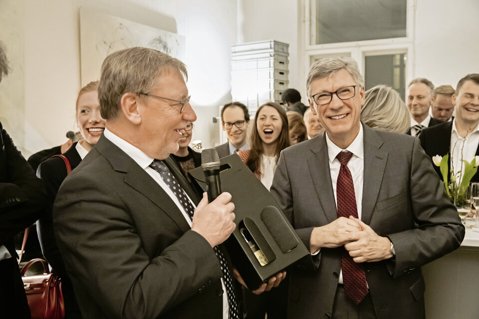 Um die „bösen Zungen“ im Zaum zu halten, überreicht Hausärztechef Ulrich Weigeldt der Obrigkeit in Person von Staatssekretär Lutz Stroppe beim Neujahrsempfang einen guten Tropfen.